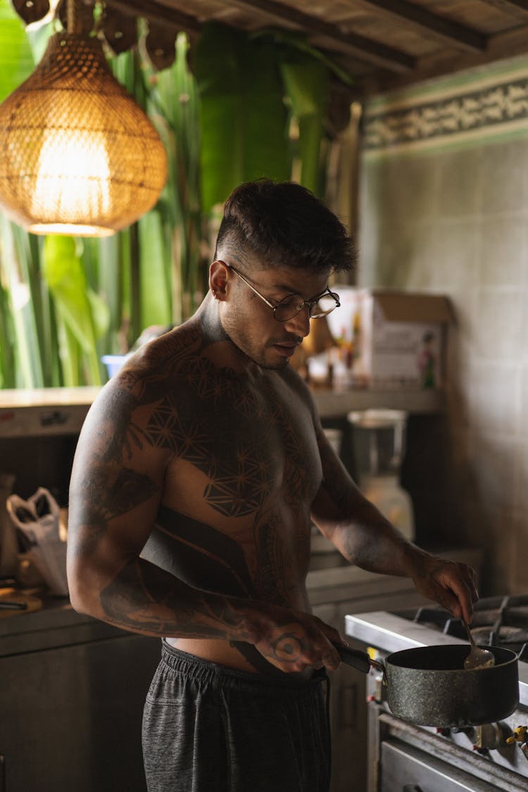 Shirtless Young Man Cooking On Kitchen Stove 