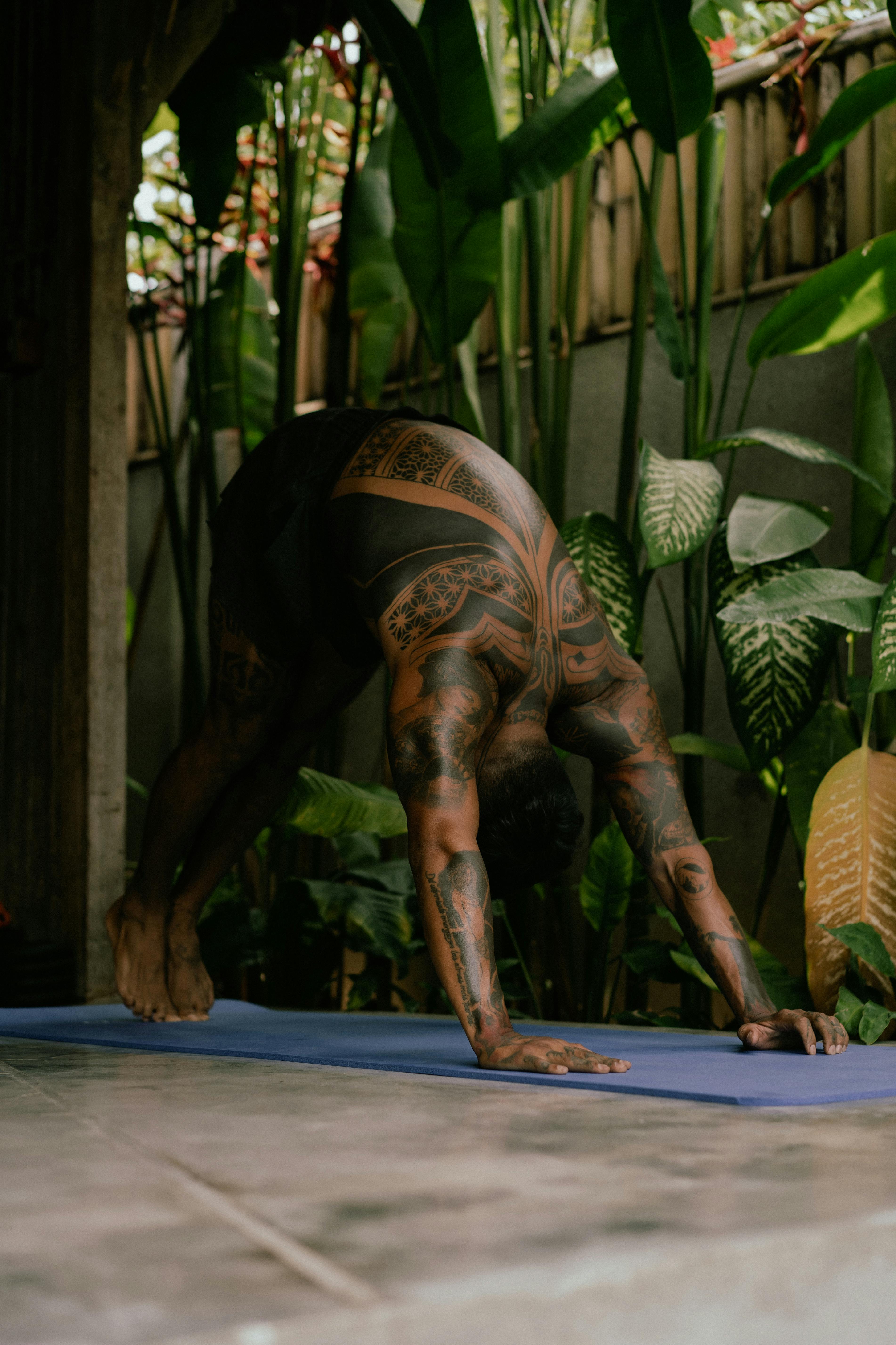 young tattooed man practising yoga