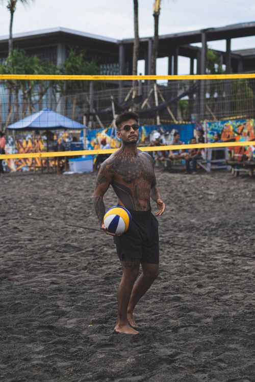 Free A tattooed man enjoying beach volleyball on a sandy outdoor court. Stock Photo