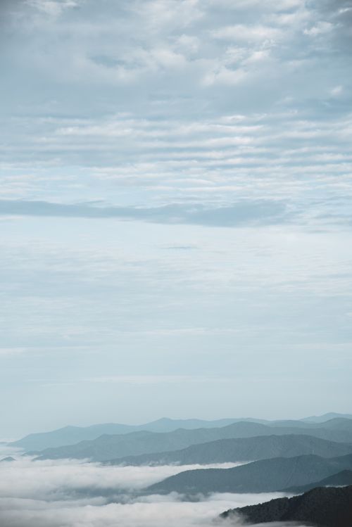 Free Serene aerial landscape showcasing misty hills beneath a vast cloudy sky, perfect for backgrounds. Stock Photo