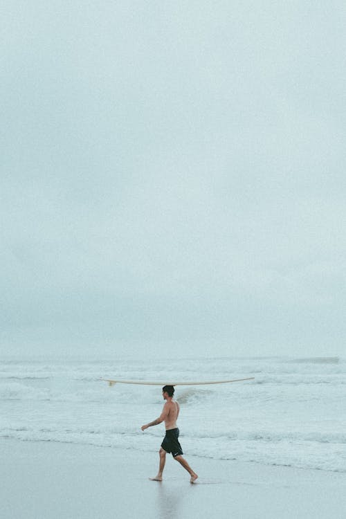 A Man Carrying a Surfboard on His Head