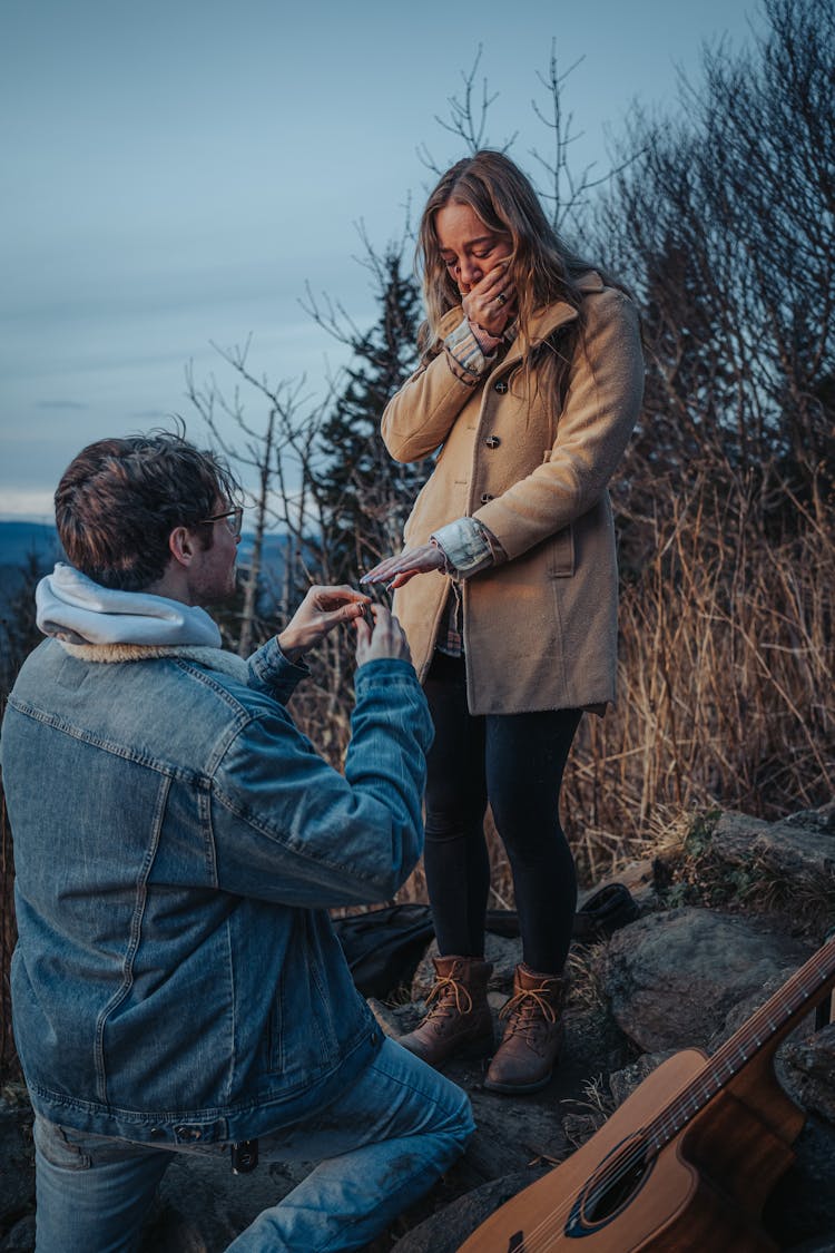 Young Man Kneeling And Proposing To Moved Woman