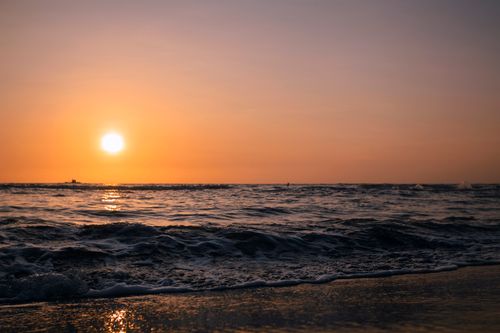 Free Breathtaking sunset over the ocean with gentle waves and vibrant sky colors. Stock Photo