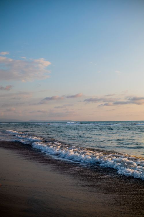 Free Beautiful shoreline at dawn with gentle waves and soft sky, perfect for relaxation and tranquility scenes. Stock Photo