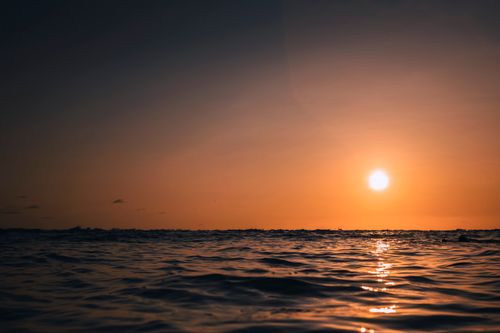 Free Beautiful ocean scene at sunset with warm hues and gentle waves. Perfect for nature lovers. Stock Photo