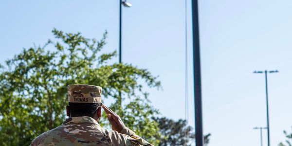 Soldiers in dress uniform saluting the American flag during a ceremony