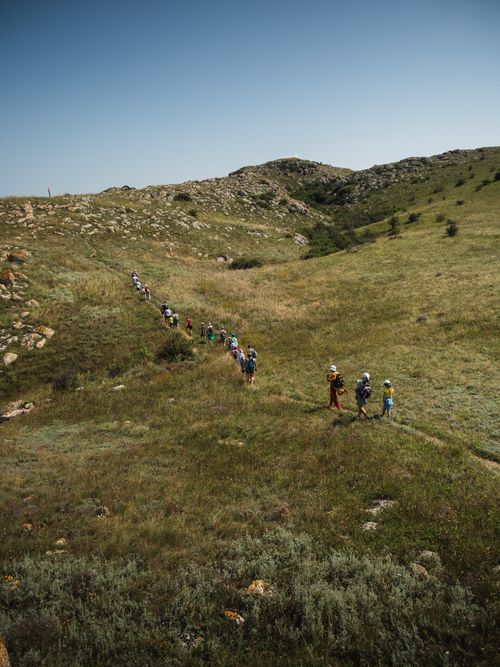 Free A group of hikers explores a grassy hill landscape under a clear blue sky. Stock Photo