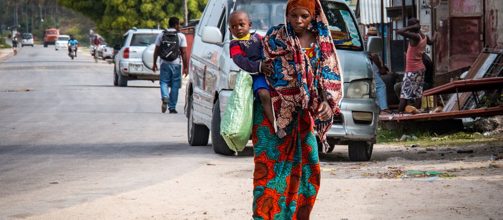 A mother and child walk together in a vibrant street scene in Zanzibar, Tanzania. — flights from Dar Es Salaam to Zanzibar