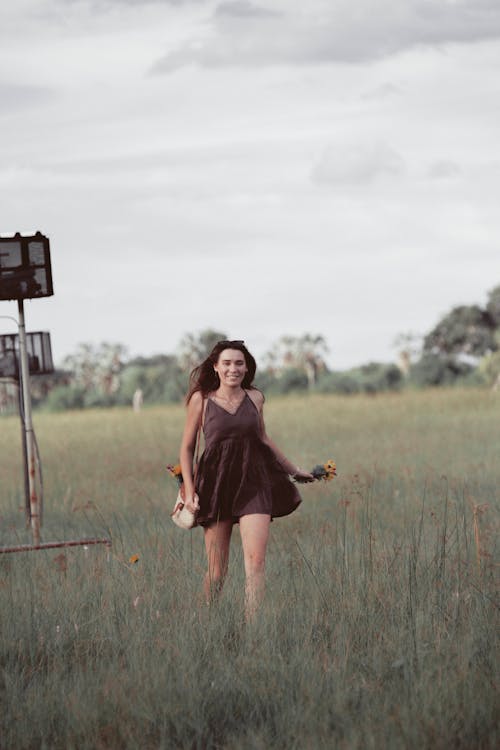 Free Woman in Black Dress Standing on Green Grass Field Stock Photo