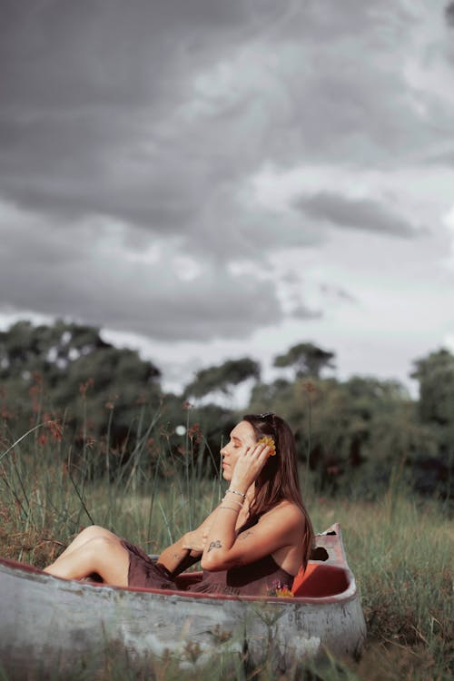 Free Woman in Brown Tank Top Sitting on Green Grass Field Stock Photo
