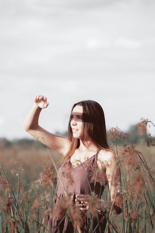 Free Woman in White Floral Dress Standing on Brown Grass Field Stock Photo