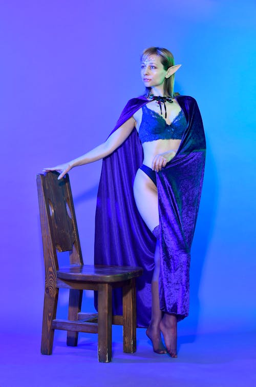 A Woman with a Cape Posing Beside a Chair