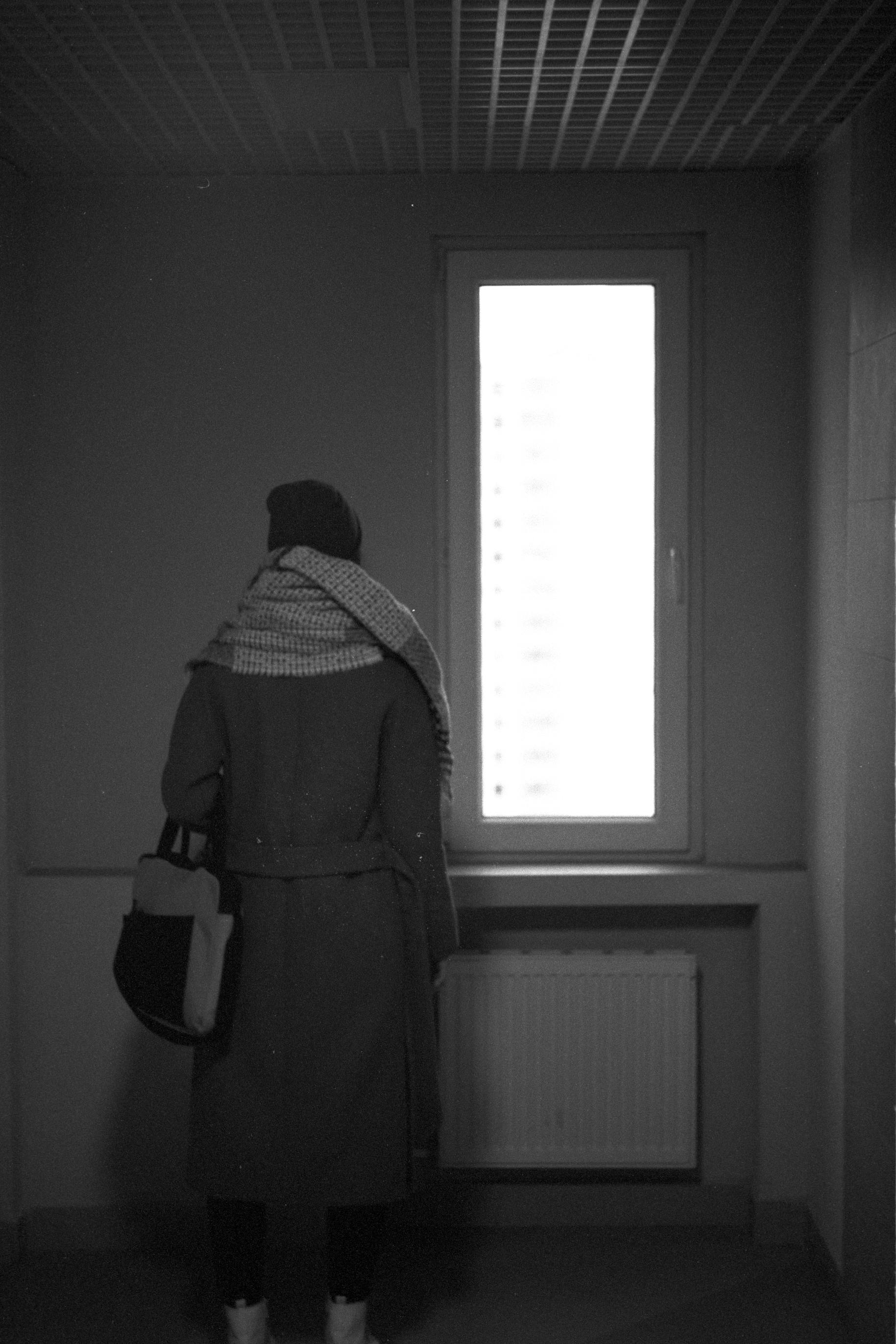 Grayscale photo of man standing near window photo – Free Cloud