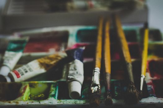 Close-up of paintbrushes and watercolor tubes on a palette, creating a creative and inspiring art scene.