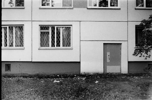 Black and white image of a building entrance with windows and a door.