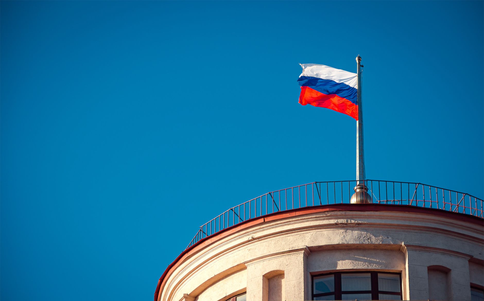 Russian national flag waving on a building in St. Petersburg under clear skies.