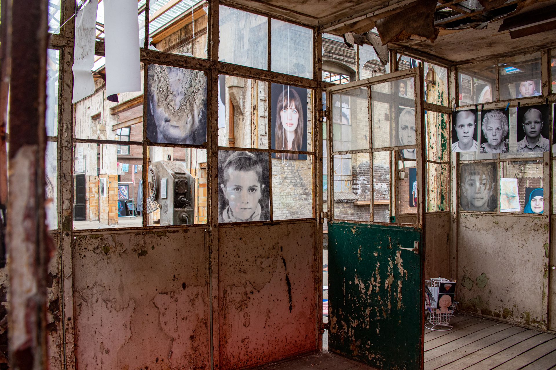 Artistic portraits display in an abandoned industrial setting, creating a striking contrast.