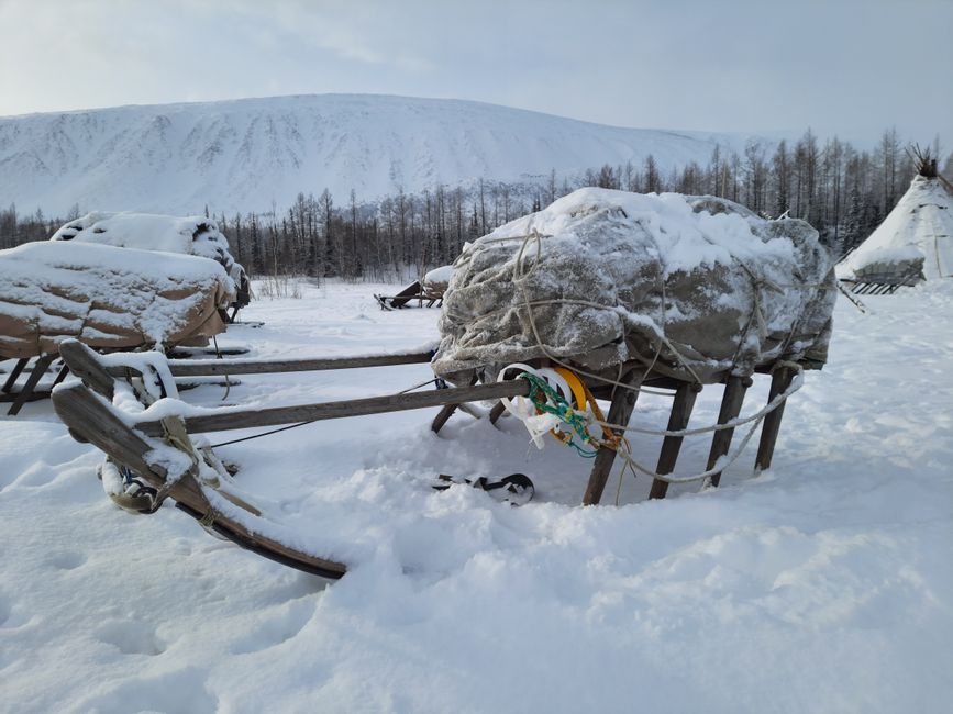 Snow-covered sled with tarp in remote winter landscape of Siberia.