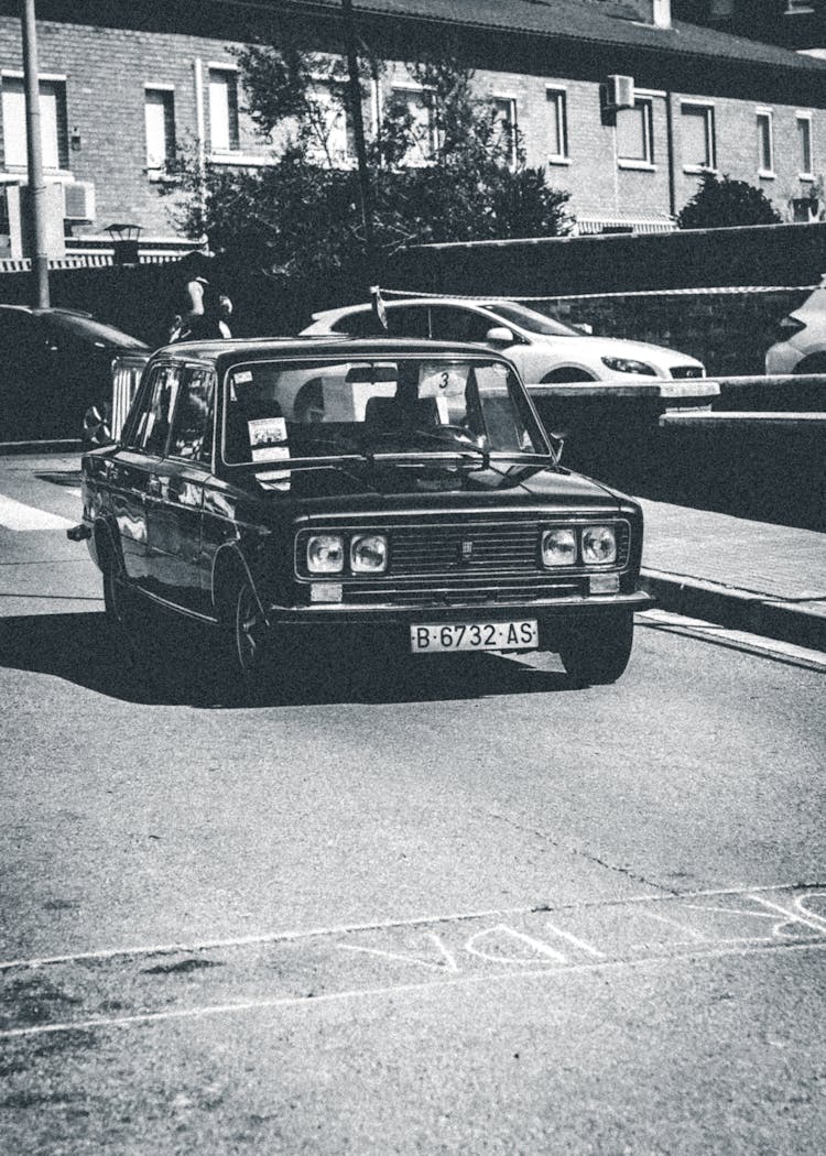 Grayscale Photo Of A Vintage Car On A Road