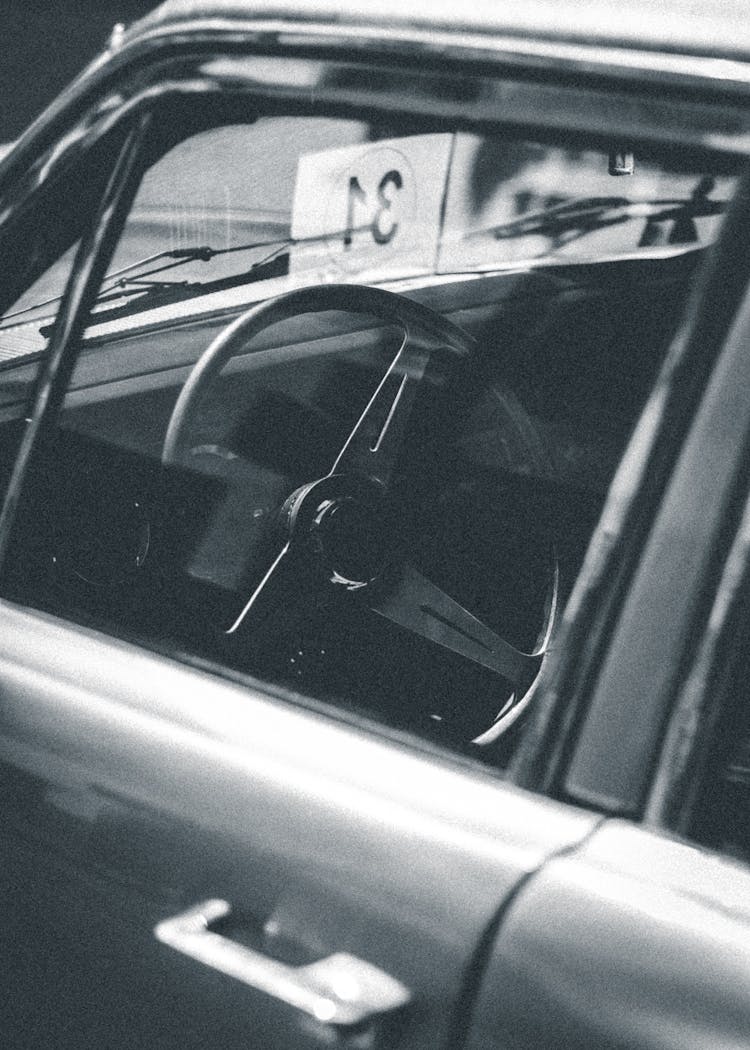 Grayscale Photo Of A Car's Steering Wheel