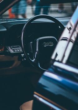 Close-up shot of a classic car interior focusing on the steering wheel and dashboard.