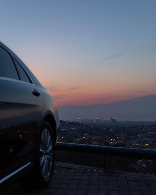 Free Parked Car on Stone Pavement with View of City during Sunset Stock Photo