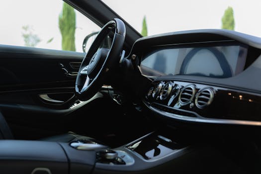 Sleek interior of a luxury car featuring a modern dashboard and steering wheel in natural light.