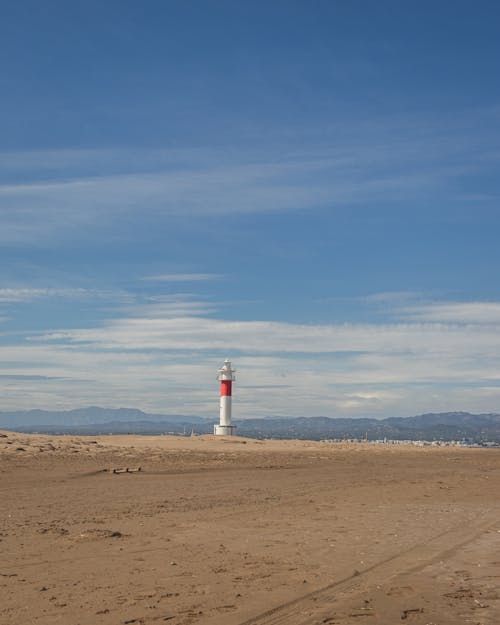 Free White and Red Lighthouse on Brown Sand Under Blue Sky Stock Photo
