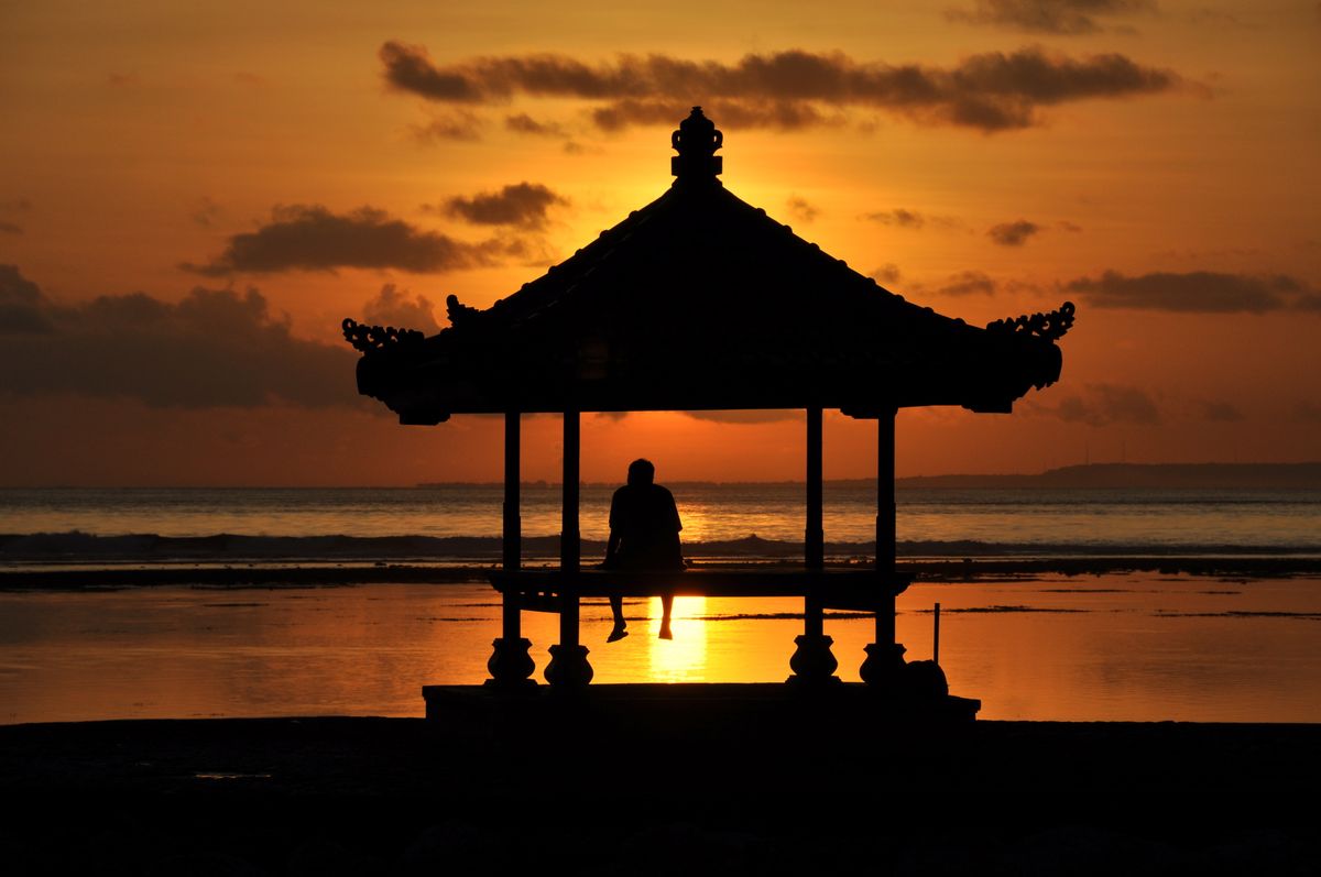 Bali - siluetă de bărbat sub un gazebo la apus, lângă mare