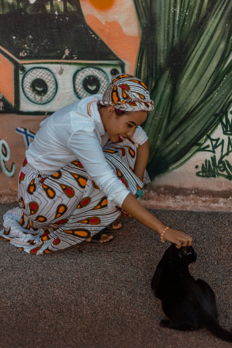 A Woman Petting A Black Cat