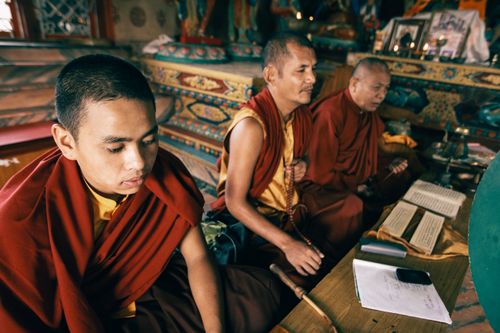 Free Three Asian monks are seated in meditation within a richly decorated temple interior. Stock Photo