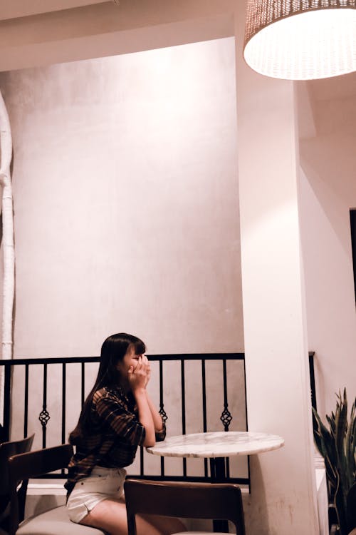 бесплатная Женщина в коричневом клетчатом платье, сидя на стуле Стоковое фото