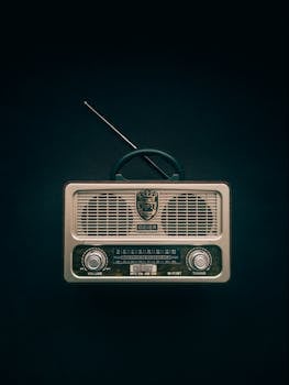 Classic vintage radio with antenna against a black background, representing nostalgia and retro music technology.