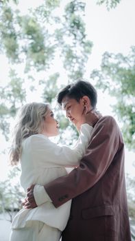 Asian couple embracing and gazing at each other lovingly under sunlight.