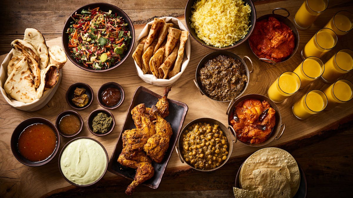A mug of frothy mushroom latte on a wooden table with dried mushrooms alongside