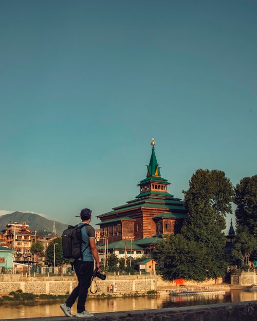Free A traveler capturing a mosque in Srinagar by the river, surrounded by mountains. Stock Photo