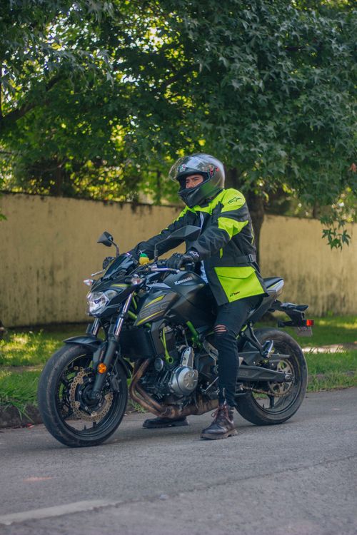 Free A motorcyclist wearing full protective gear riding through a shaded urban street. Stock Photo