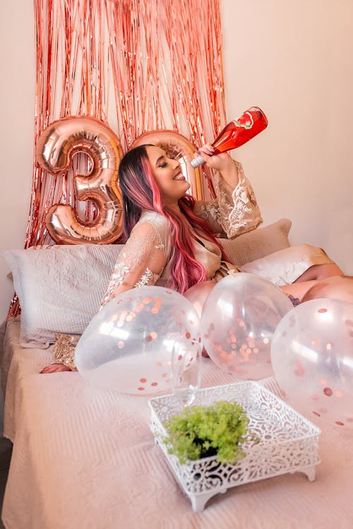Free Woman in Pink Dress Lying on Bed With Balloons Stock Photo