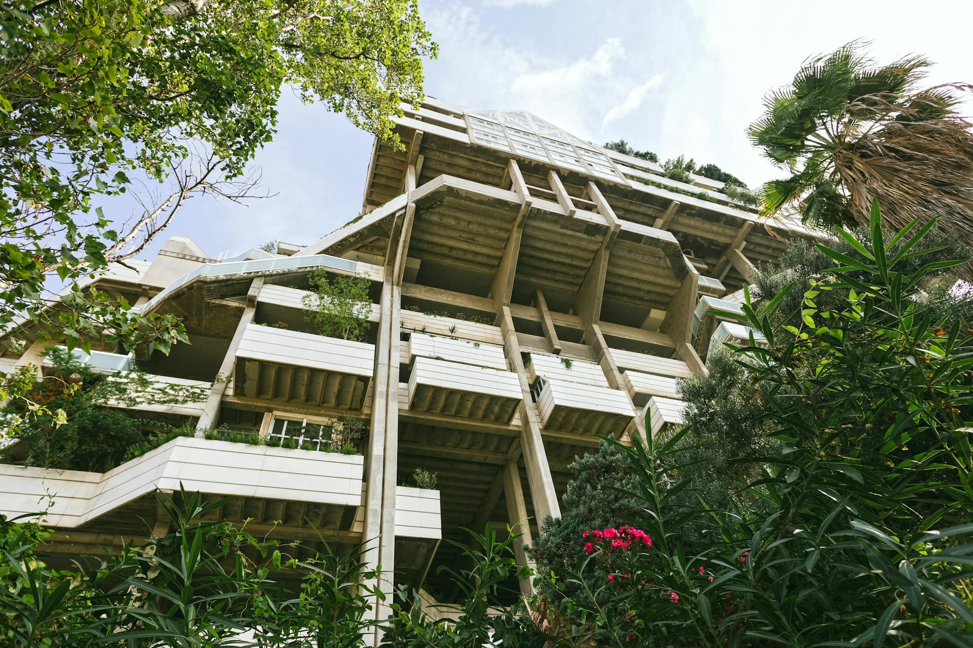 A striking low angle view of a modern building integrated with lush green foliage in Valencia.