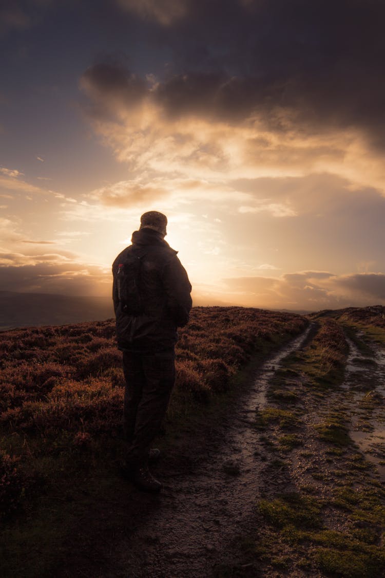 Man Standing In Muddy Field Path.