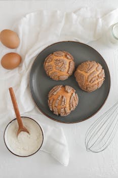 Sweet Mexican conchas with baking ingredients displayed artistically on a table. Perfect for culinary themes.