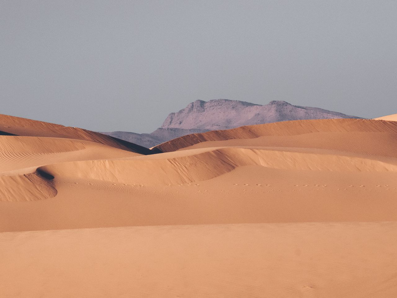 stunning view of sand dunes with distant mountains under a clear sky