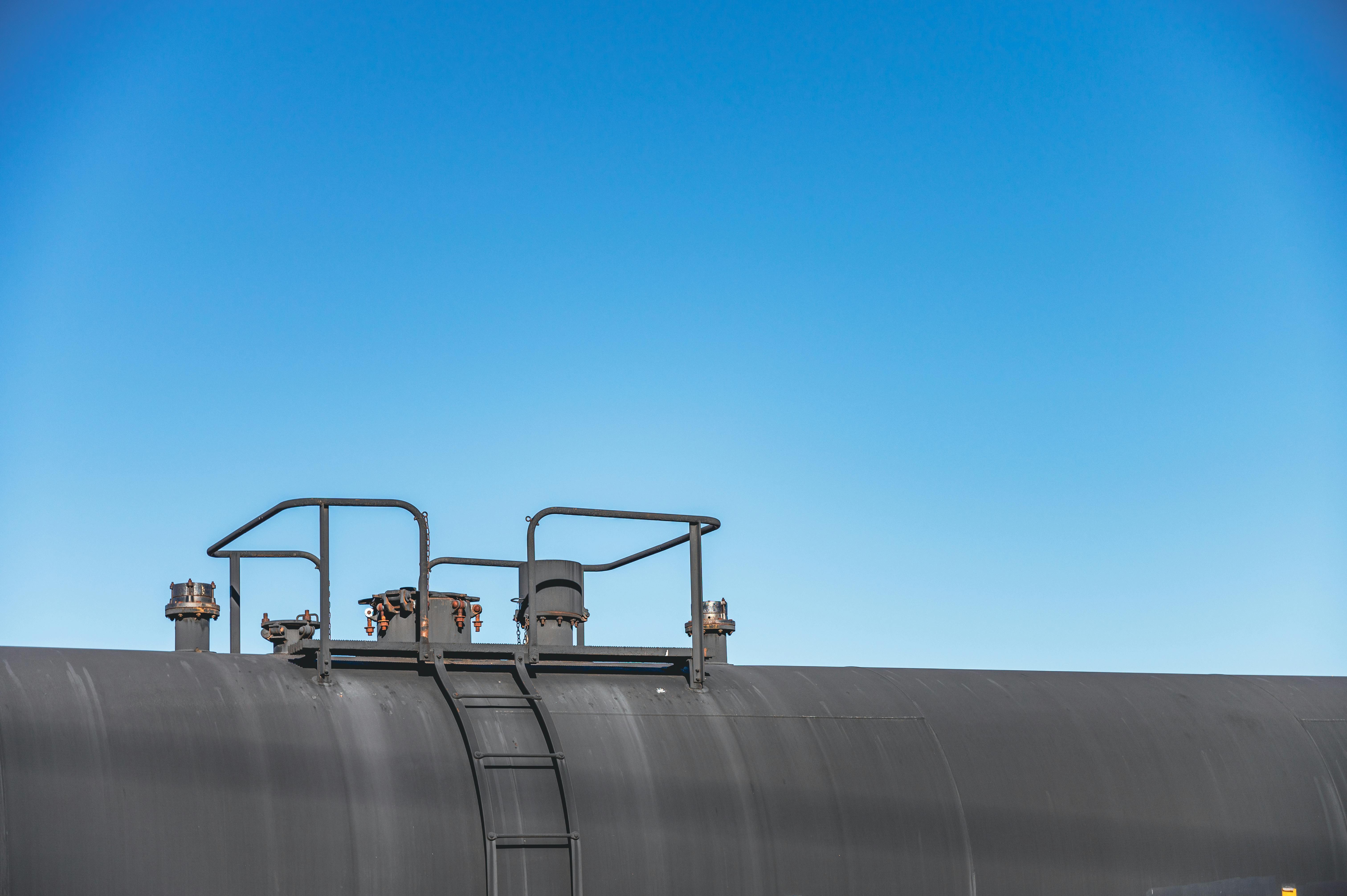 Gray metal tank and industrial structures under blue sky