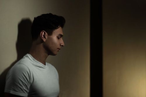 Free Portrait of a young man in dim lighting, capturing a contemplative mood. Stock Photo