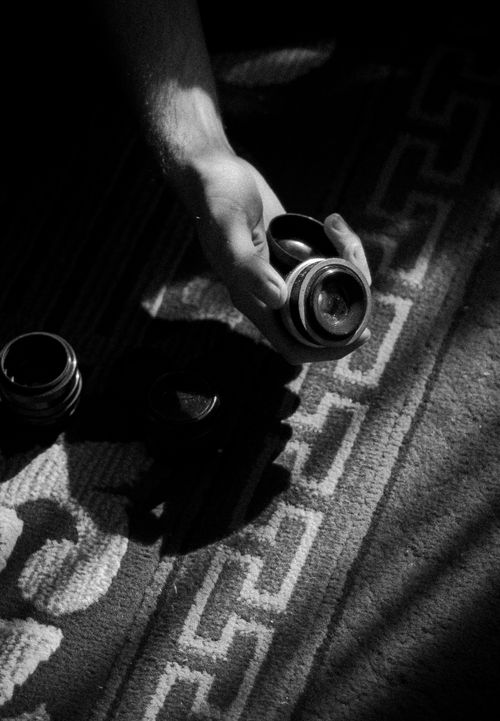 Free Monochrome image depicting a hand holding a vintage camera lens with shadows. Stock Photo