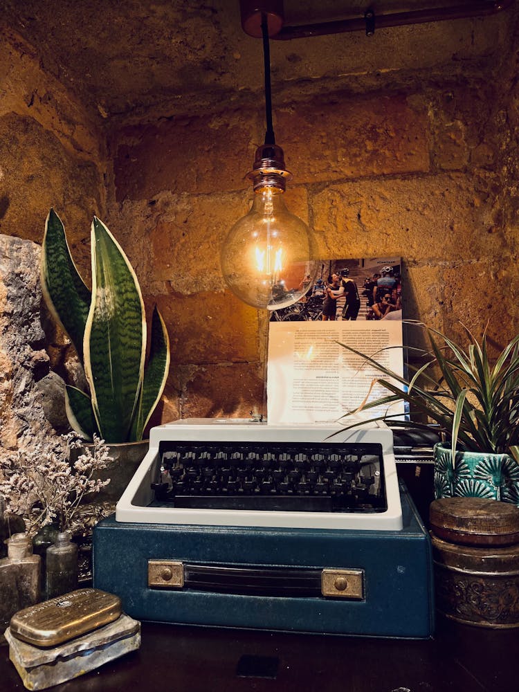 Photo Of A Typewriter Near A Light Bulb