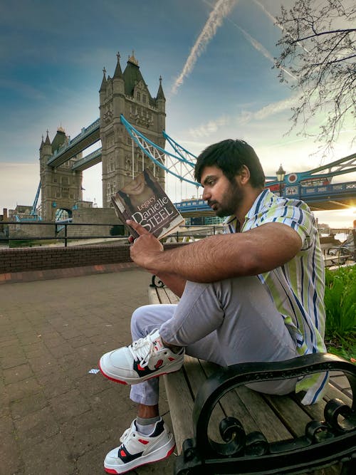 man reading book at tower bridge