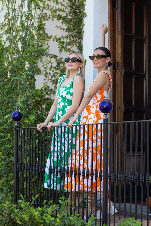 Free Two Women Wearing Dresses Holding on the Metal Railings Stock Photo