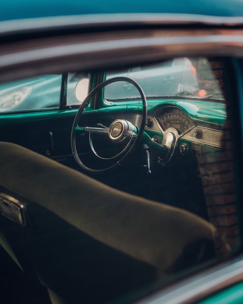 Free Close-up of a vintage car's interior showcasing a classic steering wheel and dashboard. Stock Photo
