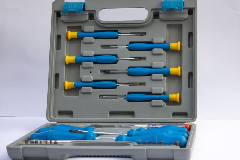 An open gray plastic toolbox displaying an assorted set of screwdrivers with blue handles.